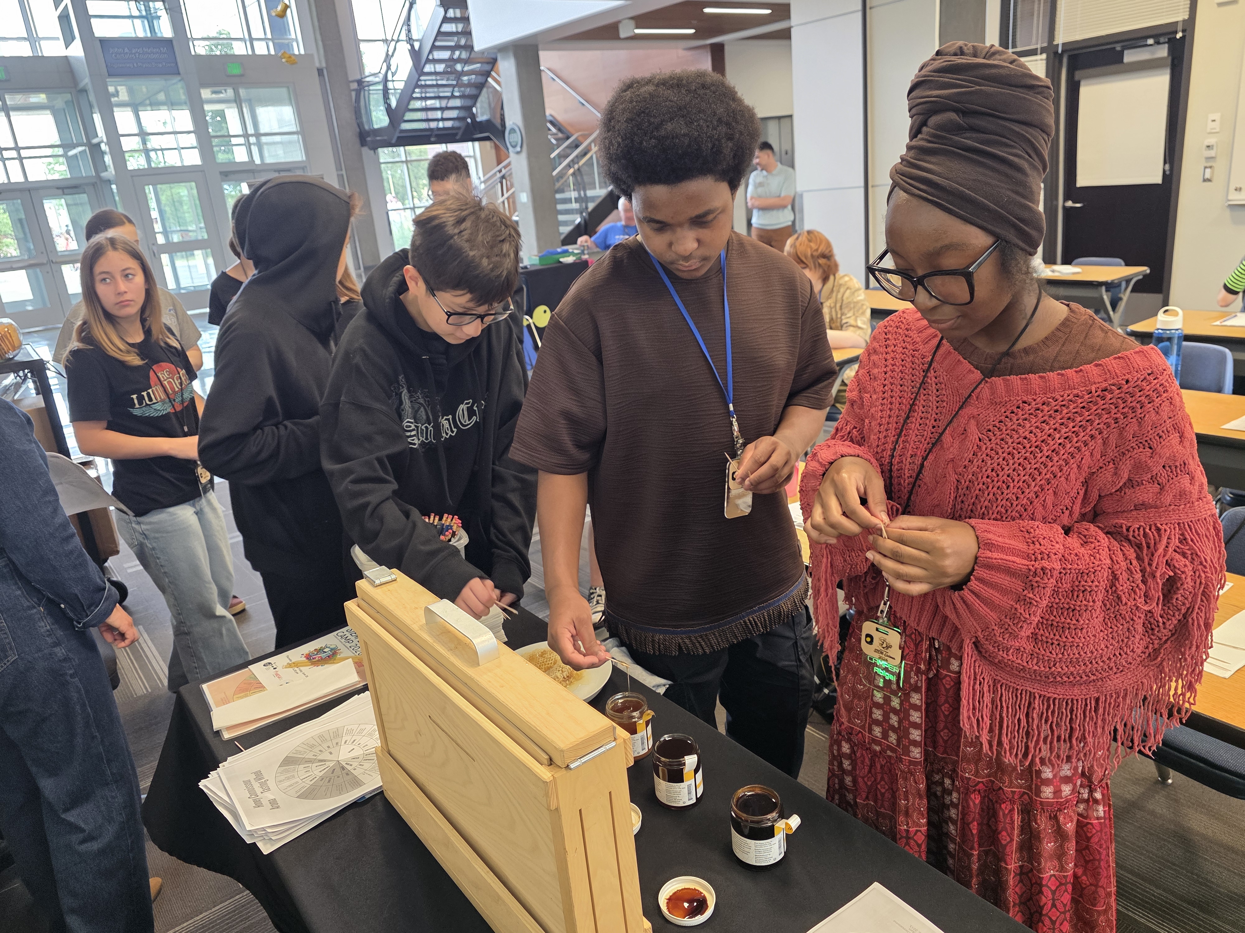 Students line up next to a table with dishes of honey