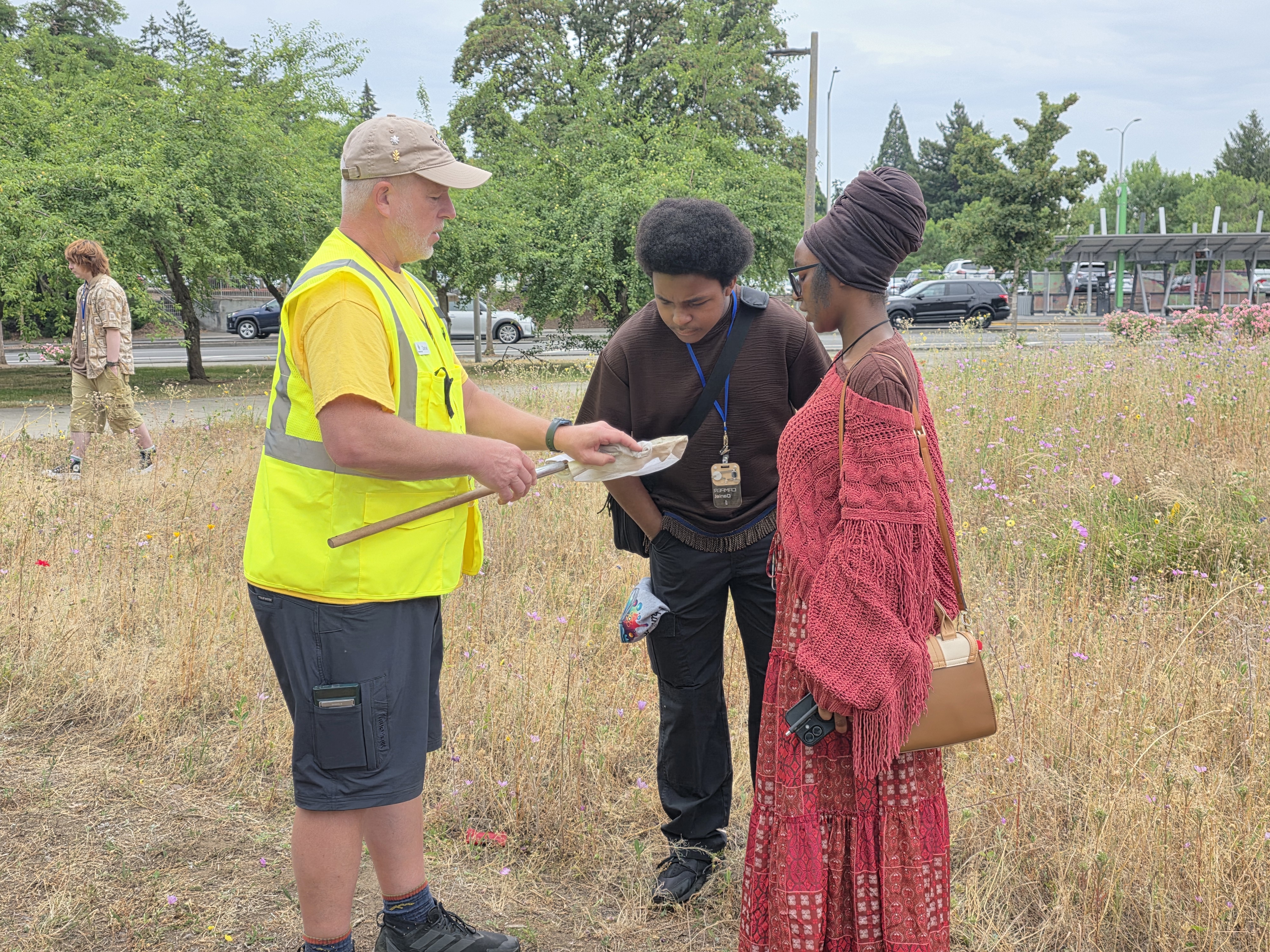 Two students look in a net with Vancouver Bee Project's Daniel Szumlas 
