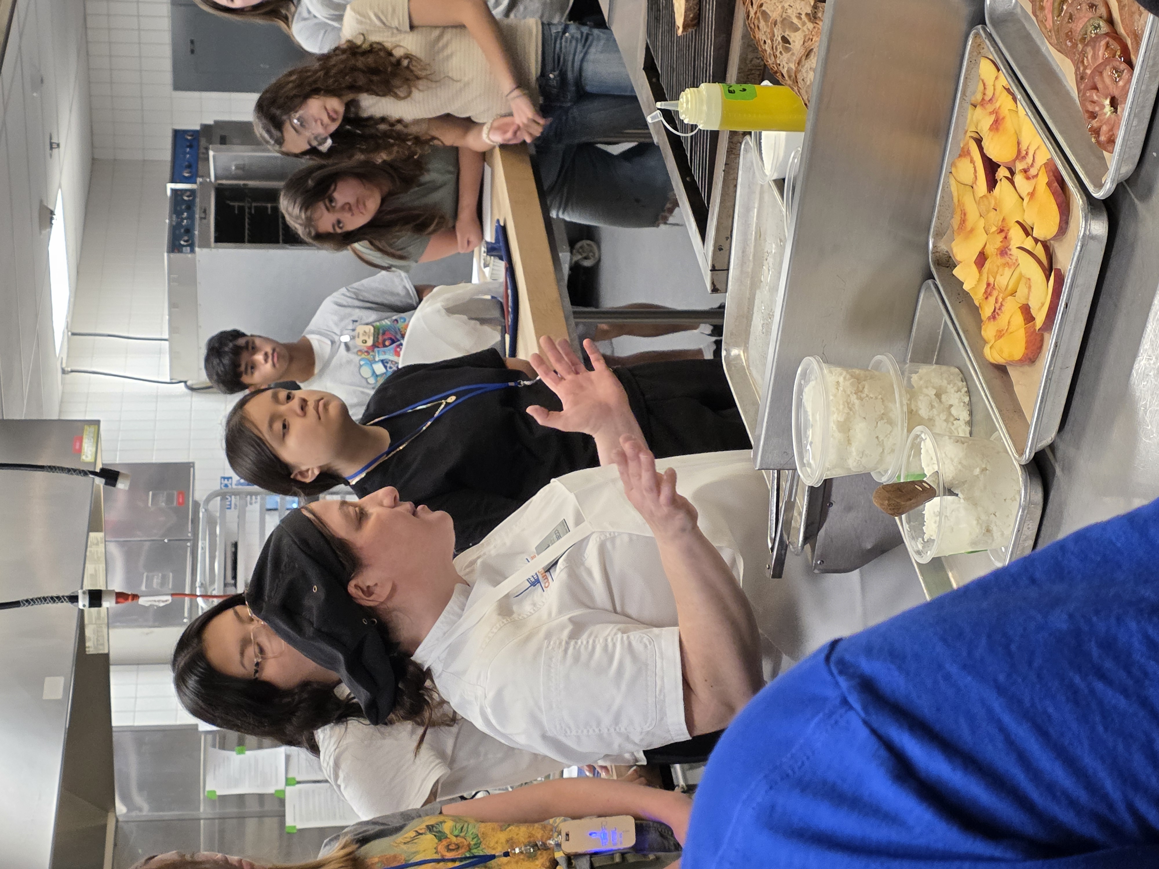 Chef Rebecca and students gather around stove in the MCI