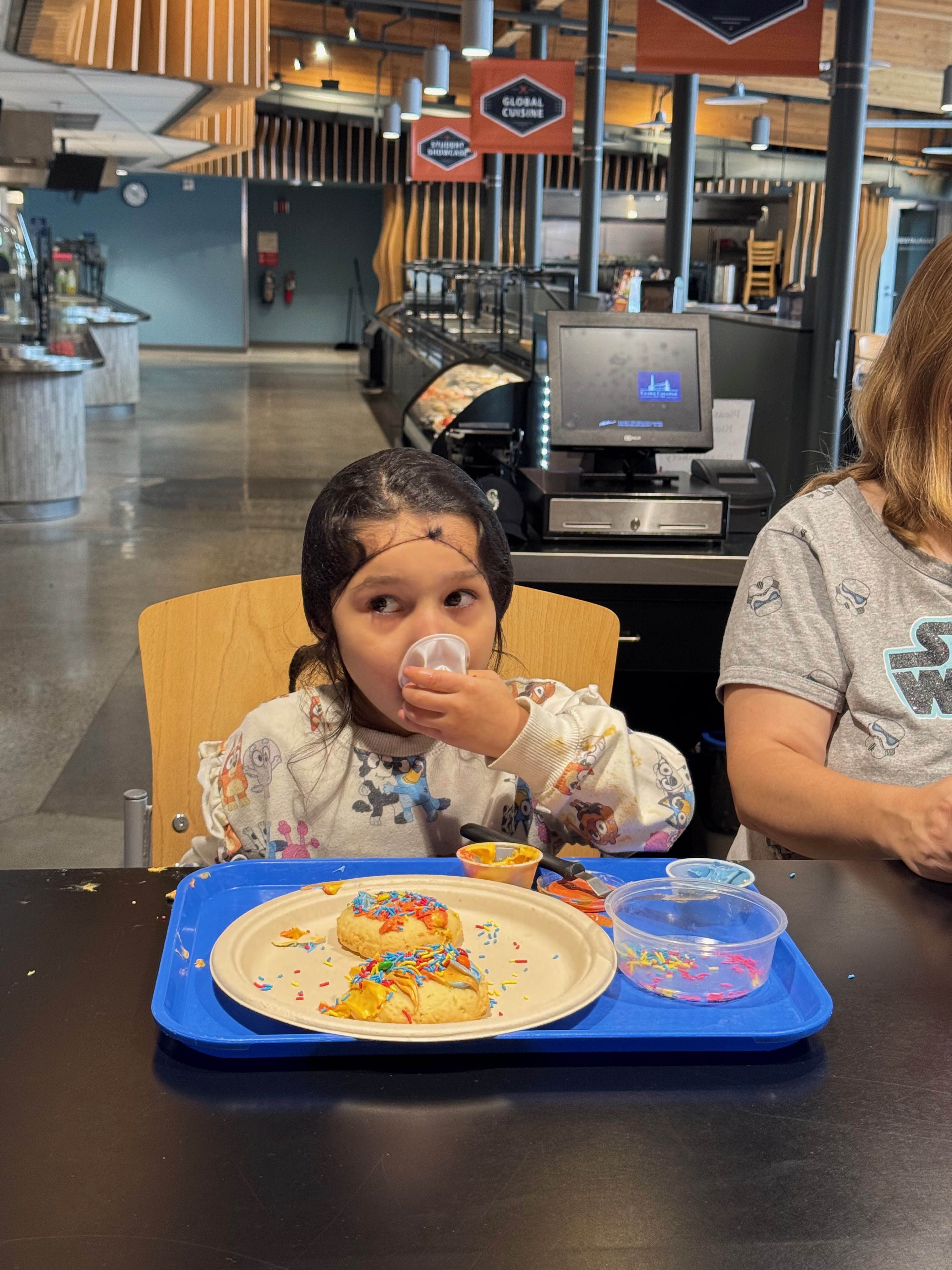 A little girl in a hairnet eating sprinkles straight from the container