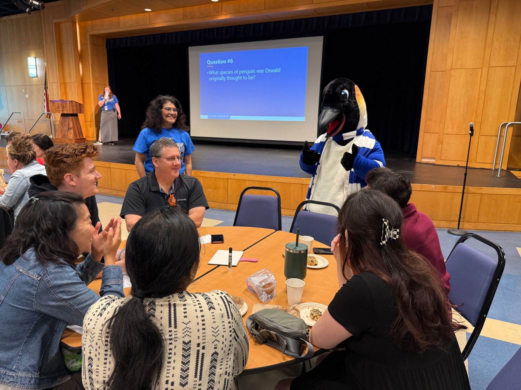 A group of people sitting at a table next to Oswald the Penguin