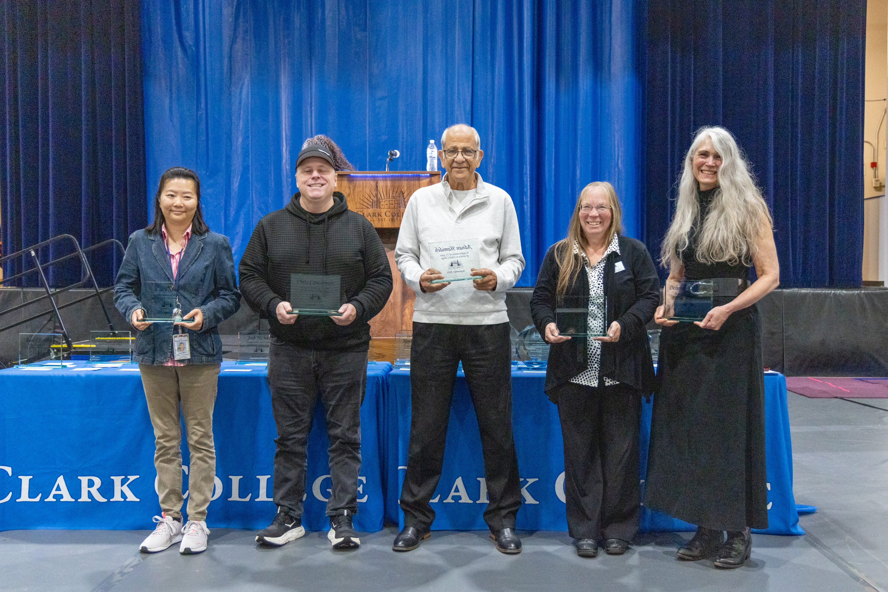 25-year employees stand holding their awards