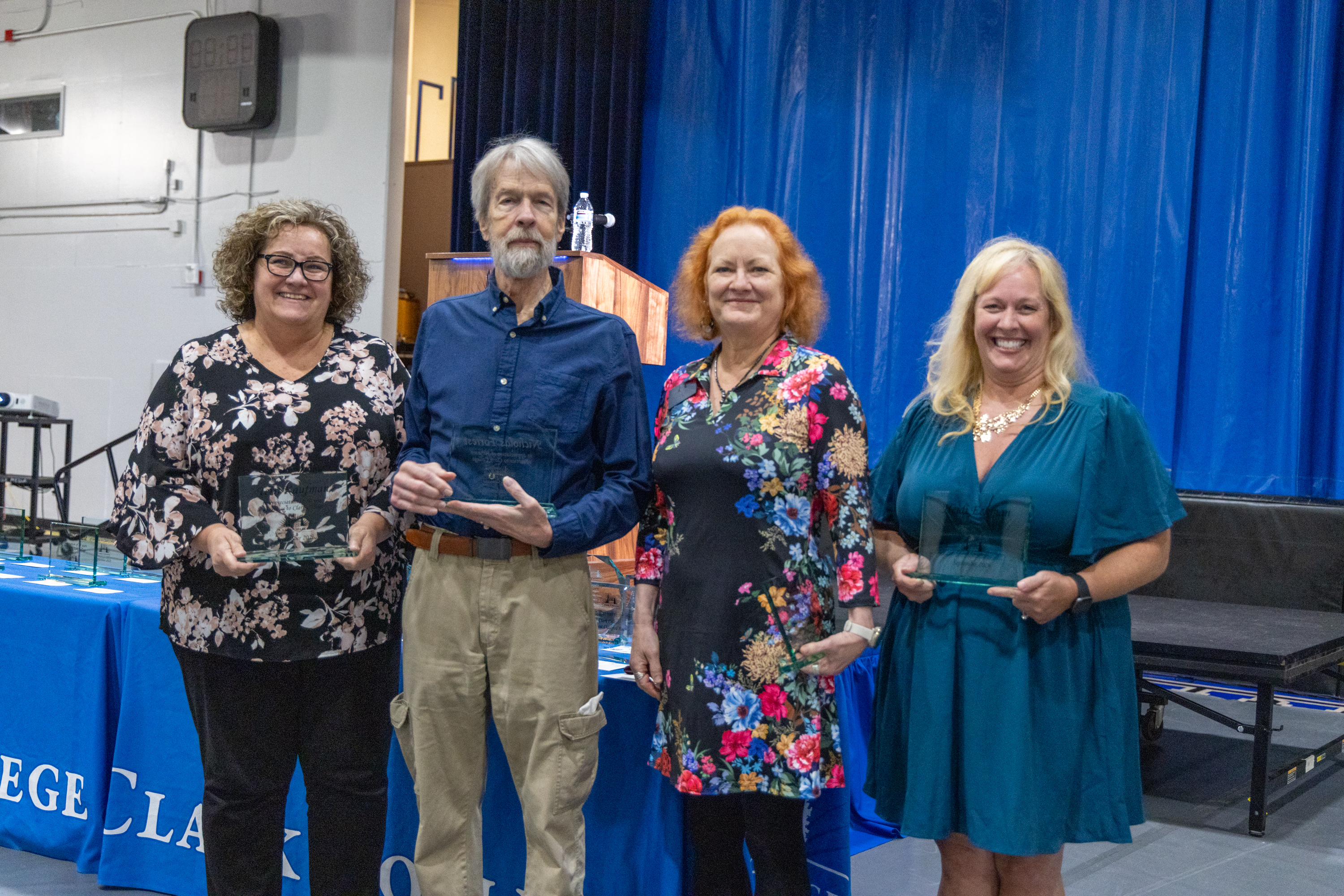 30-year employees stand holding their awards