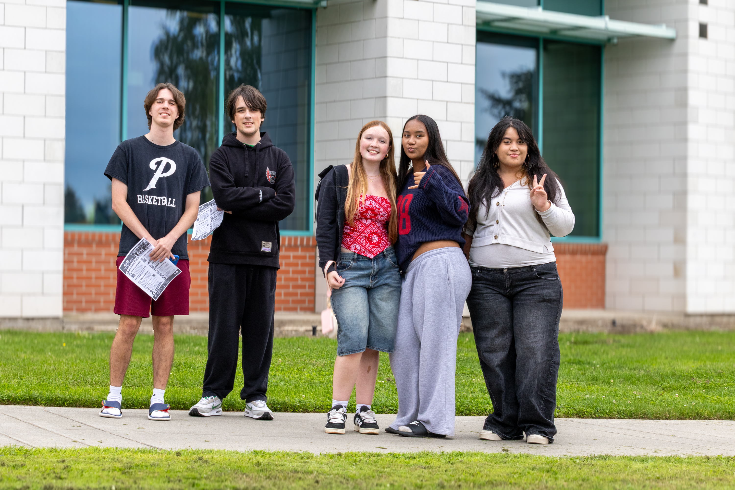 Five students stand together outside of a campus building
