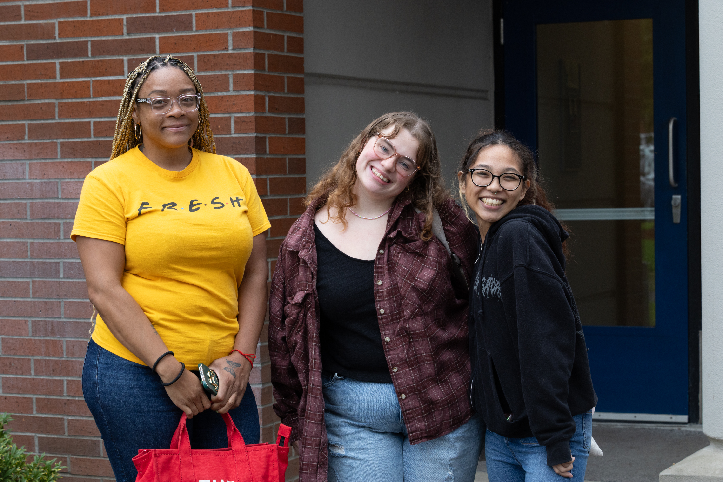 Three students stand together smiling