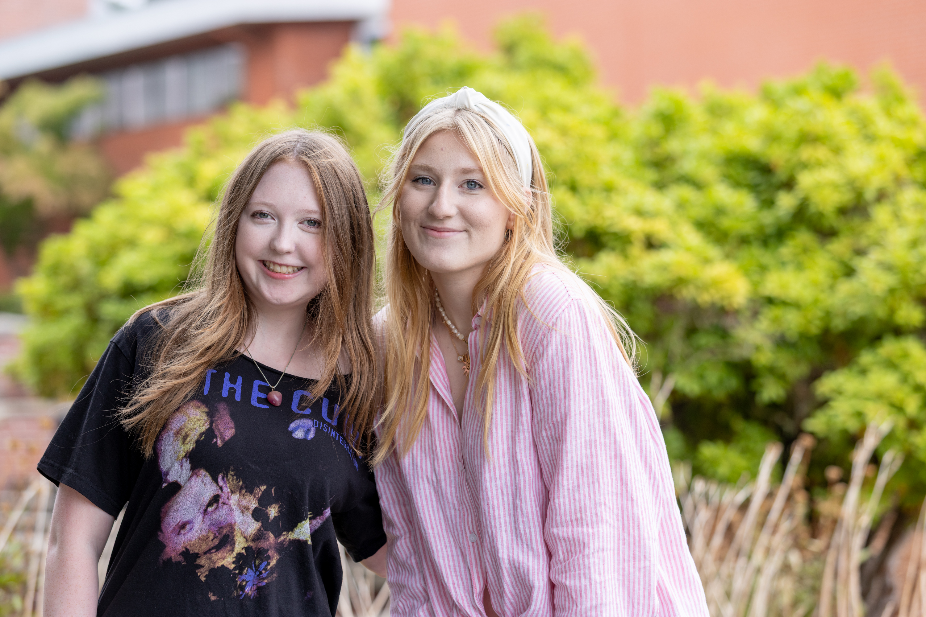 Two students stand together smiling