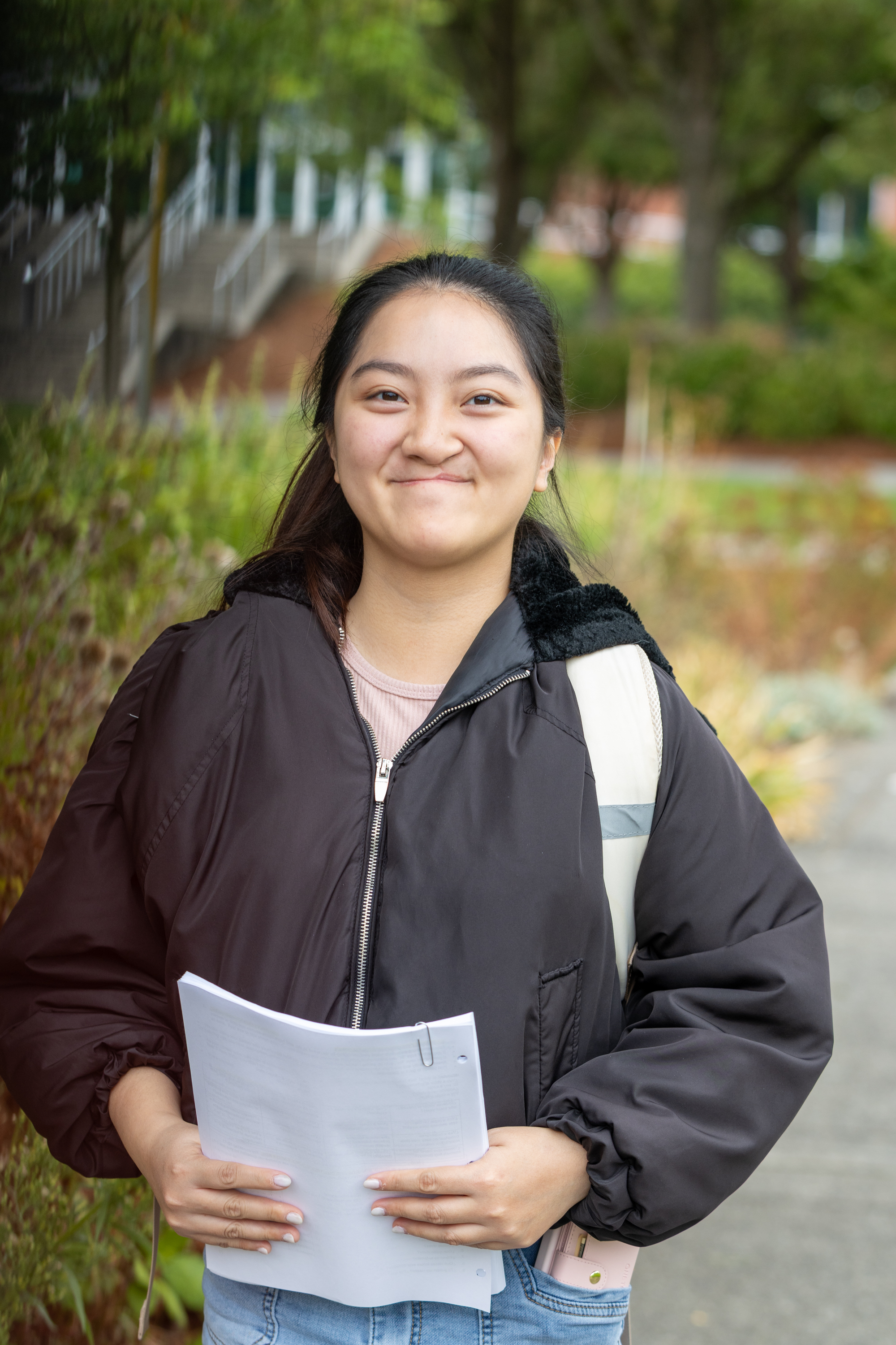 Student smiles while holding a stack of papers