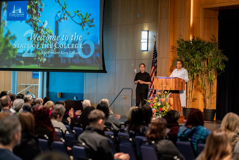 Dr. Edwards and an interpreter stand on stage in Gaiser Hall during the college's annual State of the College