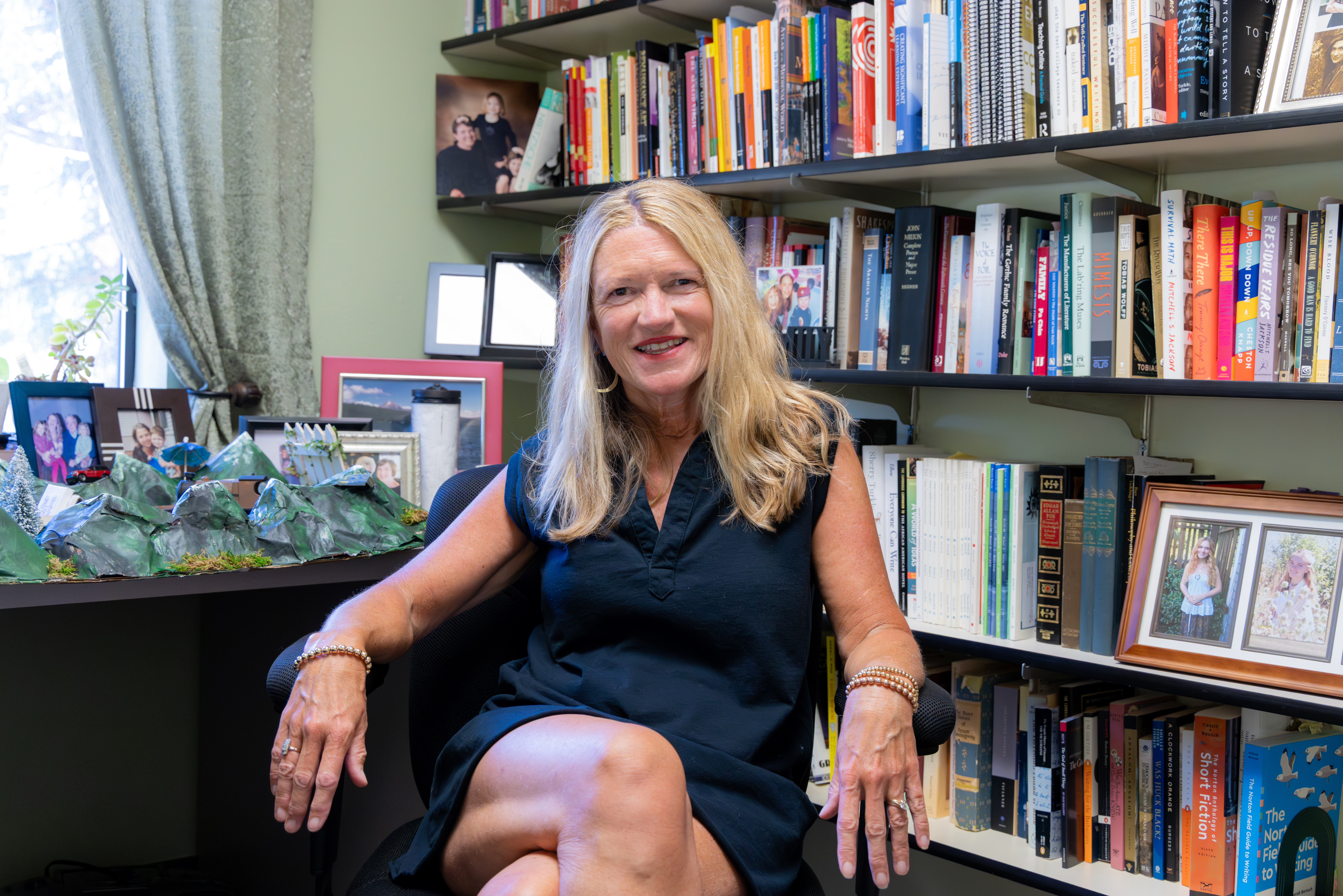 Jill Darley-Vanis sitting in a chair in front of shelves of books