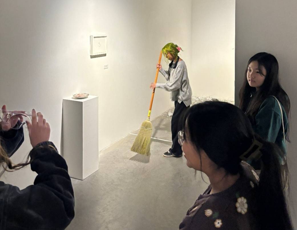 A ceramics student sweeps up a broken mug that they threw on the ground.