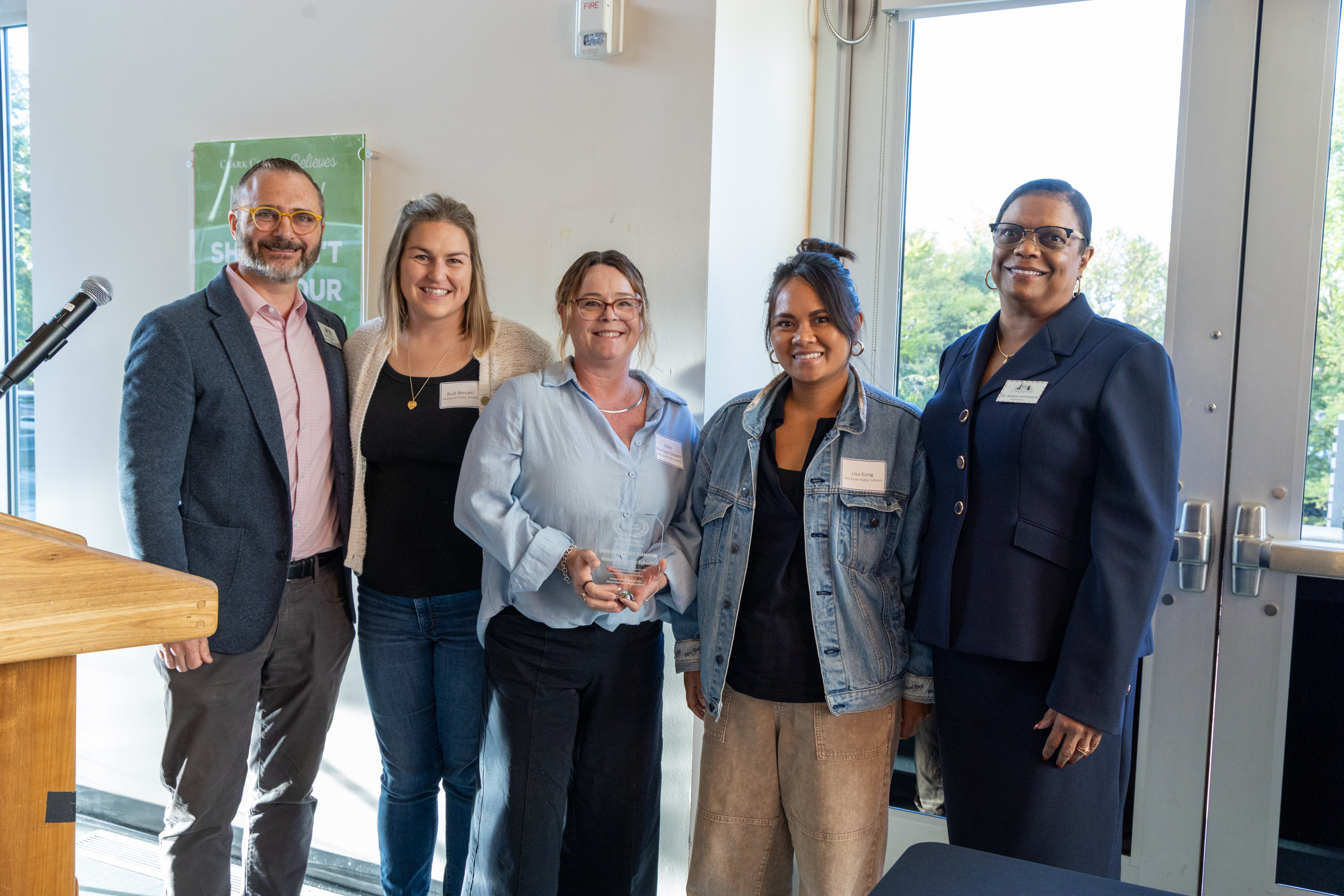 VPS Assistant Director of Career and Technical Education Katie Siewert, Lisa Kong, and Senior Human Resources Specialist Rudi Bersani stand with Dr. Karin Edwards and Don Romesburg, all are smiling and Katie holds the award.