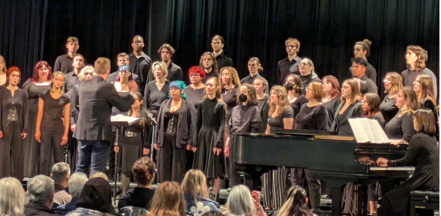 A college concert choir performing under a conductor at a choral festival.