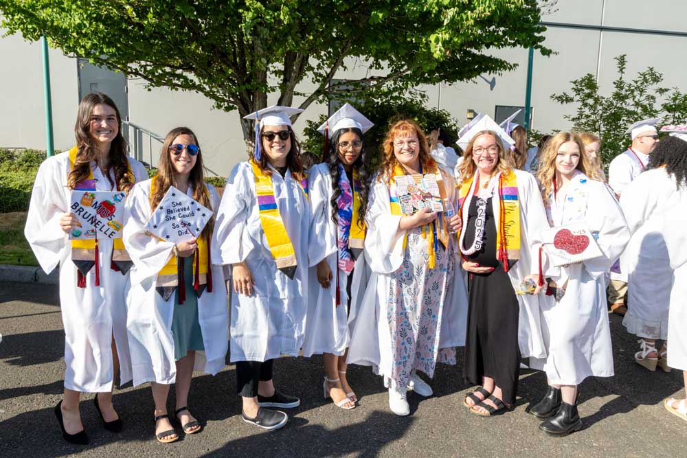 Group of BASTE graduates in caps and gowns standing together at the commencement ceremony.