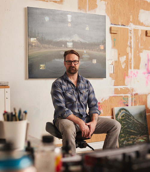 A person sitting on a chair with a painting visible in the background.