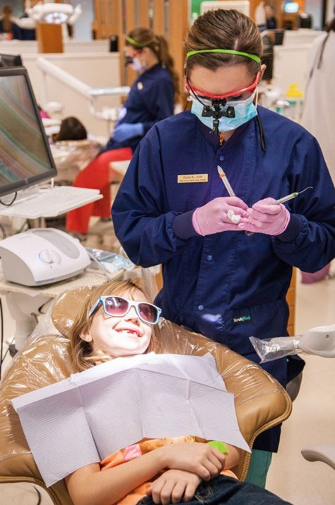 dental hygenist working on child in a dental chair