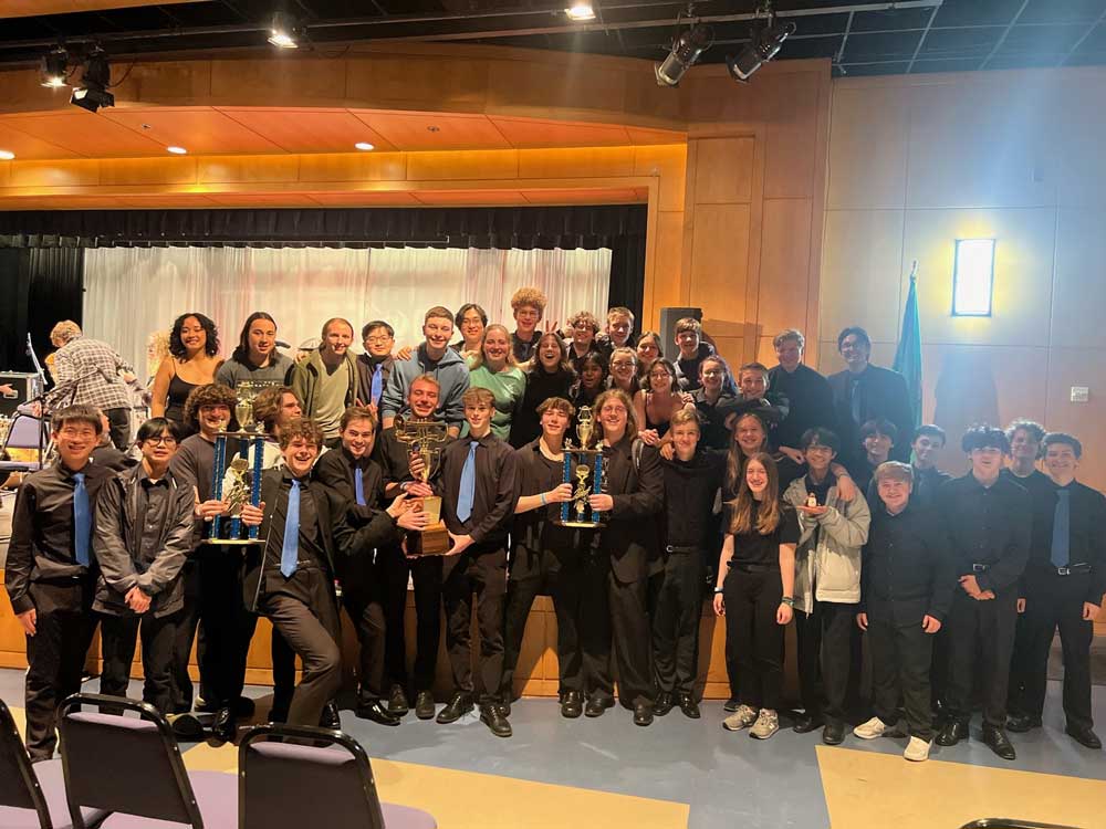A group of high school jazz band students holding trophies.