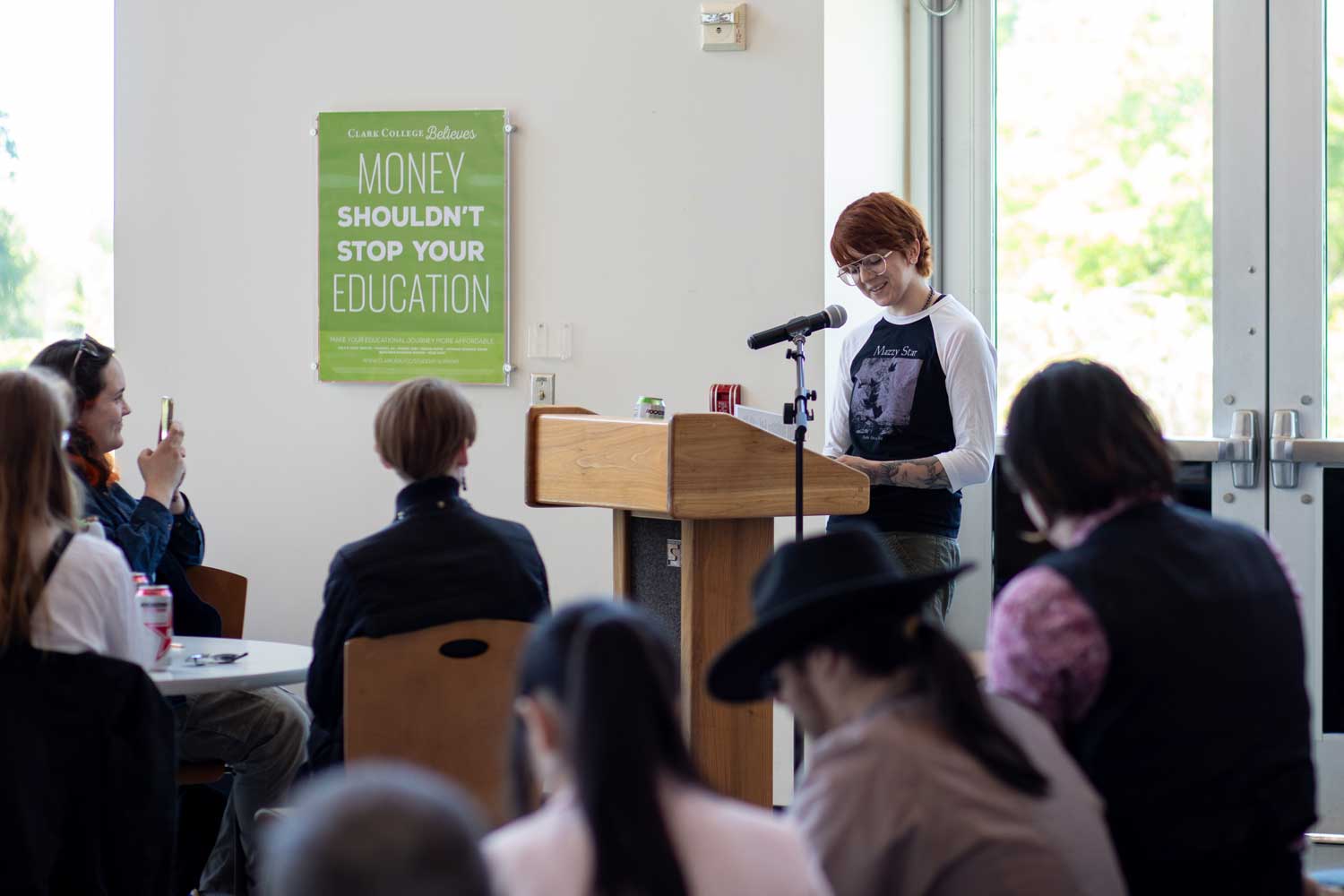 A person speaking at a podium with a microphone, addressing an audience in a conference setting.