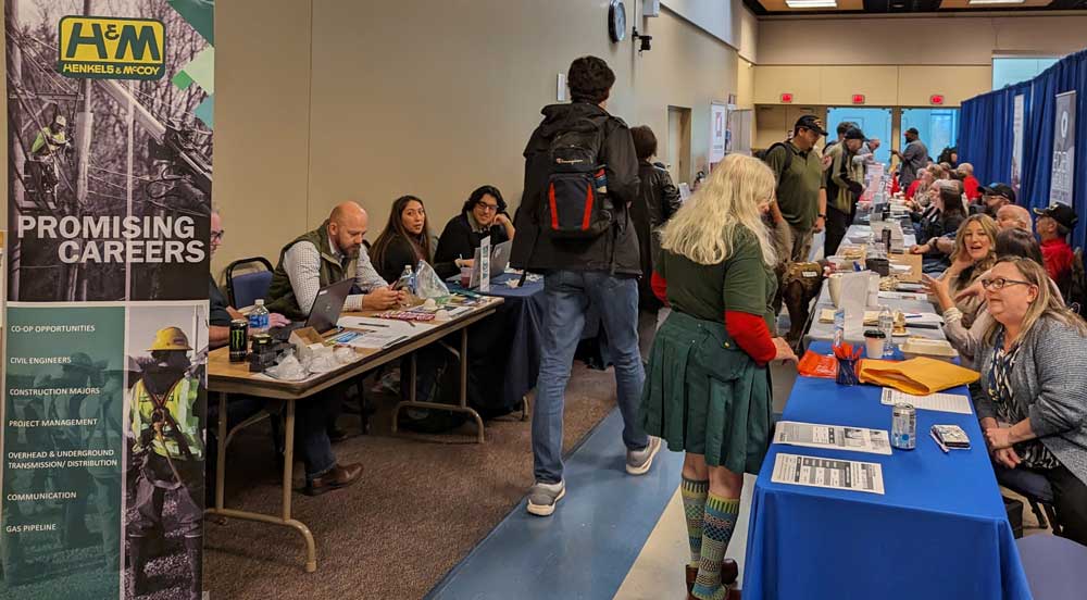 Students and employers interacting at the VCOE Career and Resource Fair, with tables lined up displaying informational signs, brochures, and banners for different organizations.