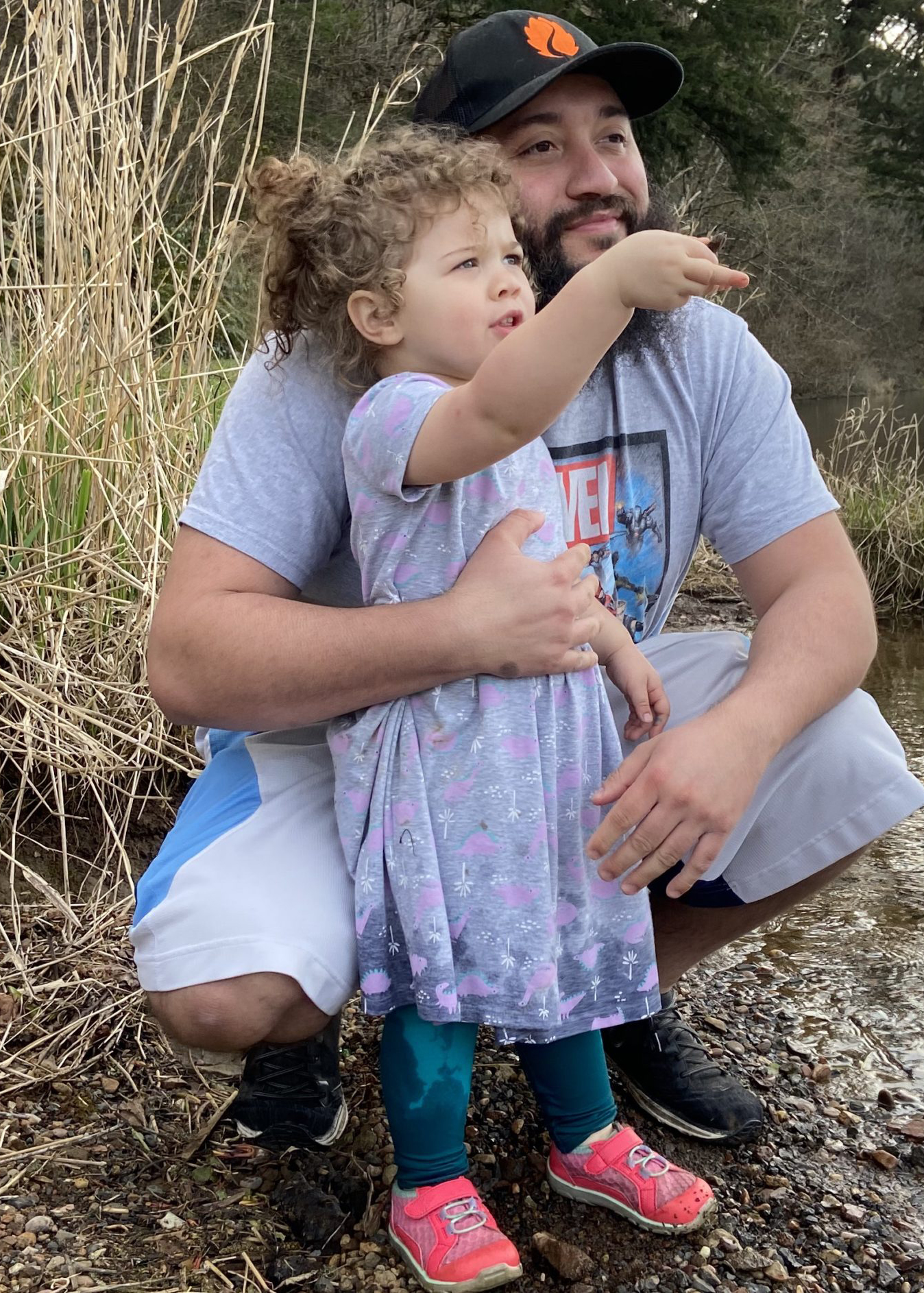 Marcell kneeling next to his with daugher pointing at the river